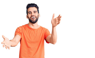 Fototapeta premium Young handsome man with beard wearing casual t-shirt smiling cheerful offering hands giving assistance and acceptance.