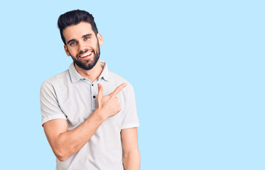 Young handsome man with beard wearing casual polo cheerful with a smile of face pointing with hand and finger up to the side with happy and natural expression on face