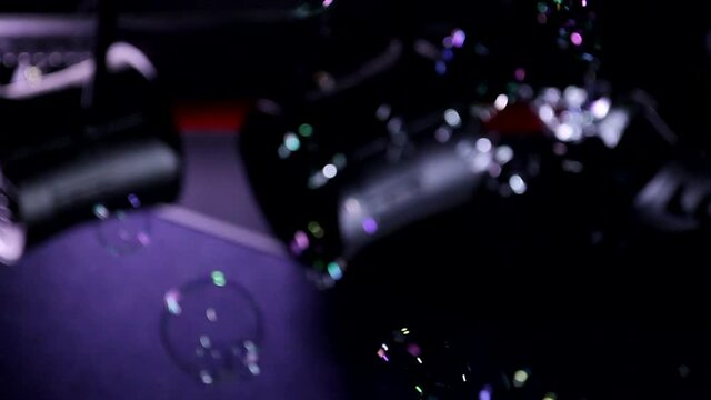 Close up autofocus animation shot of soap bubbles moving flying in air chaotically on neon violet blue dark background