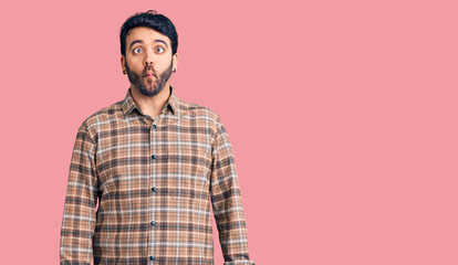 Young hispanic man wearing casual clothes making fish face with lips, crazy and comical gesture. funny expression.