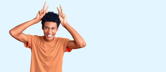 Young african american man wearing casual clothes posing funny and crazy with fingers on head as bunny ears, smiling cheerful