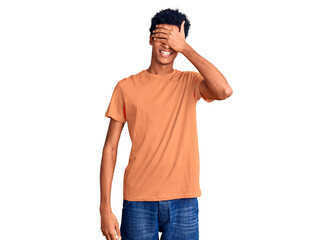 Fototapeta premium Young african american man wearing casual clothes smiling and laughing with hand on face covering eyes for surprise. blind concept.
