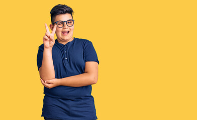 Little boy kid wearing casual clothes and glasses smiling with happy face winking at the camera doing victory sign. number two.