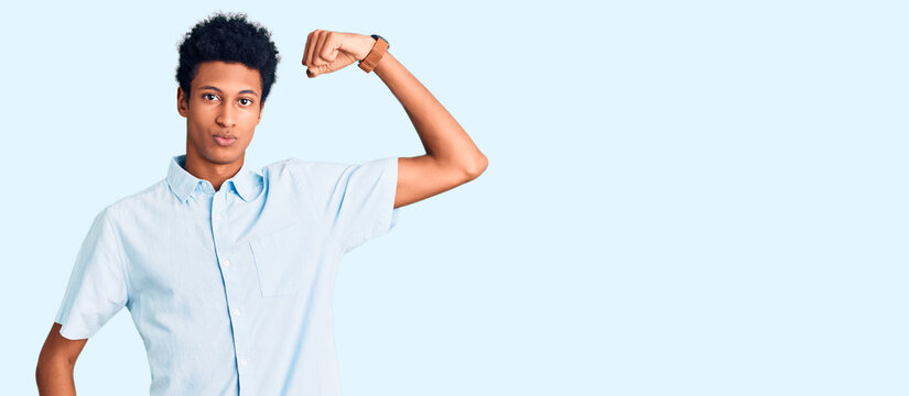 Young african american man wearing casual clothes strong person showing arm muscle, confident and proud of power