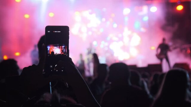 Silhouette of Woman Hands Making Video with Smartphone at Live Rock Concert. Slow Motion