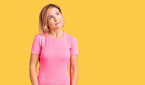 Young blonde woman wearing sportswear smiling looking to the side and staring away thinking.