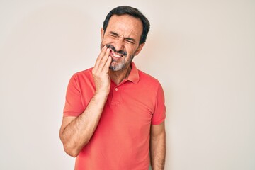 Middle age hispanic man wearing casual clothes touching mouth with hand with painful expression because of toothache or dental illness on teeth. dentist