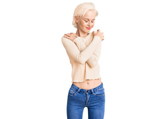 Young blonde woman wearing casual clothes hugging oneself happy and positive, smiling confident....