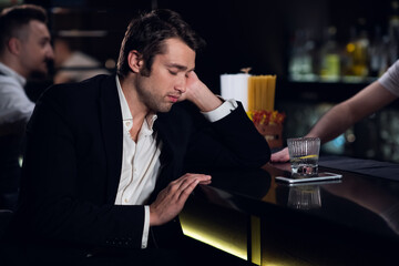 a tired man fell asleep at the bar in a restaurant.