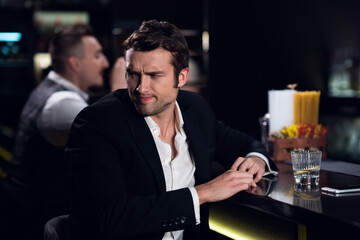 a young man drank a lot at the bar, sitting drunk at the bar with a cocktail.