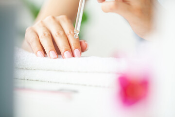 Moisturizing oil for cuticles, woman cares for hands and nails.