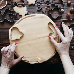 Woman cutting cookies of raw gingerbread dough