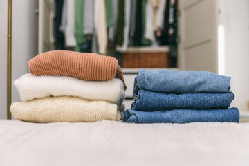 Stacks of sweaters and jeans. Cleaning out wardrobe, clothes placed on hangers and in drawers