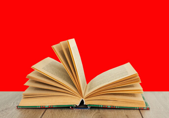 Open book textbook in colorful cover on a orange red background. Back to school distance home education.Quarantine concept of stay home.
