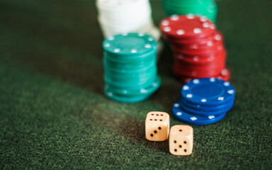 Casino poker chips stack dice on green felt background.