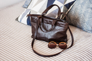 Woman brown leather bag on the gray sofa, female accessory.