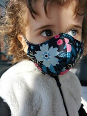 Little Brazilian girl looking to the side using mask outdoors