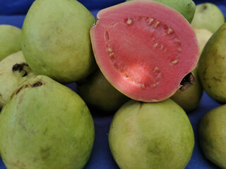 Close of guavas with one of them cut in half at a street market