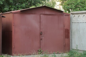 one old red  iron garage with closed gates on the street