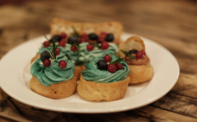 cakes on a plate - cupcakes and eclairs, close up
