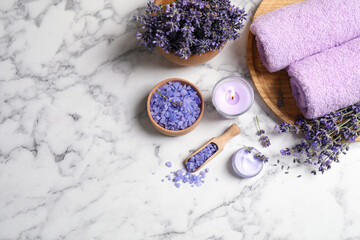 Cosmetic products and lavender flowers on white marble table, flat lay. Space for text