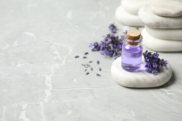 Stones, bottle of essential oil and lavender flowers on marble table. Space for text