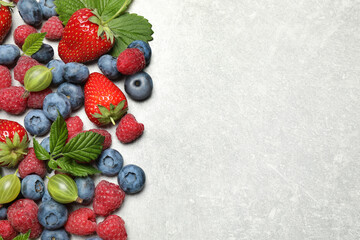 Mix of fresh berries on light table, flat lay. Space for text