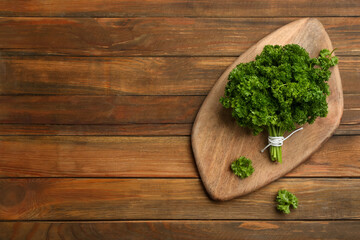 Bunch of fresh curly parsley on wooden table, flat lay. Space for text