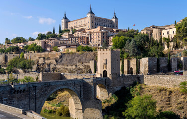Morning at Toledo - Panoramic morning view of historic city Toledo at Puente de Alcántara, a Roman arch bridge at front of east city gate Puerta de Alcántara and over Tagus River. Toledo, Spain.