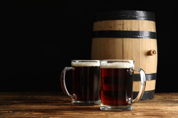 Glass mugs of delicious kvass and barrel on wooden table