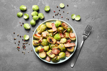 Delicious fried Brussels sprouts with bacon served on grey table, flat lay