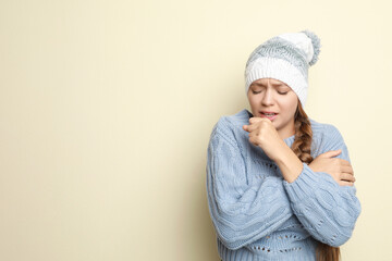 Young woman wearing hat coughing on light background, space for text. Cold symptoms