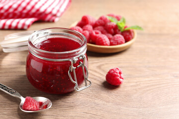 Sweet raspberry jam and fresh berries on wooden table