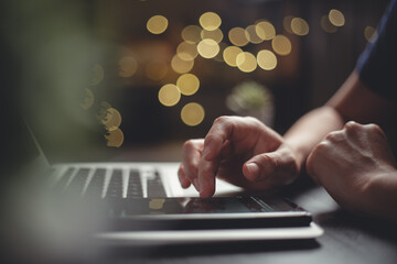 Close up shot of hands using smart phone typing message for searching with laptop on glow bokeh background.