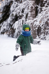 Fototapeta na wymiar Portrait of a cute little boy in warm clothes who play with snowflakes in winter sunny frosty day, beautiful seasonal card, Siberia nature, kids play, having fun in wonderland forest
