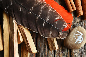 A top view image of a brown feather with various smudge sticks and Reiki healing symbol. 