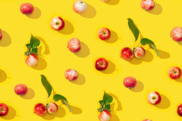 Seamless creative pattern from small red apples and green leaves with dark shadows.