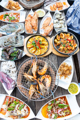 Seafood buffet grill with raw shrimp, shellfish, crab, squid prepared empty, comes in a white plate, looks delicious, delicious, ready to eat, available on a wooden table with a grill.