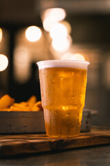 glass of beer on the table with fries on the background
