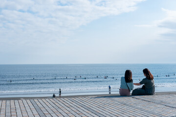 Fototapeta premium サーファーが浮かぶ湘南の海を眺める２人の女性