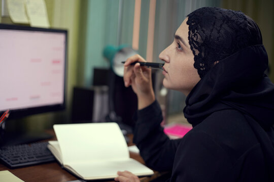 Middle eastern female entrepreneur. Busy Arabian businesswoman. A middle-aged woman in traditional Arabian clothing hijab or abaya working writing on notepad