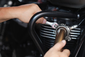 Mechanic using a wrench and socket on exhaust pipe of a motorcycle .maintenance,repair motorcycle...