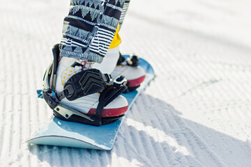 Close-up snowboarder legs on the snowboard on the fresh velvet snow