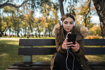 A beautiful caucasian woman sitting on a bench and using her smartphone. Copy space