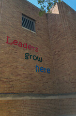 school building with inspirational Leaders grow here text on brick