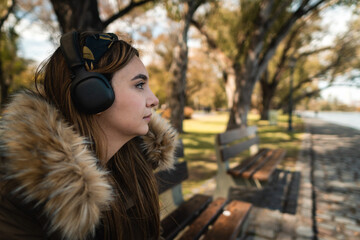 A pretty caucasian woman listening music at park and looking at side. Copy space