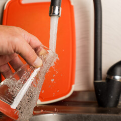 A man pours tap water into a glass flask.