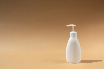 white dispenser bottle, for spa cosmetic products on beige or brown background. Antibacterial soap. Place for your text