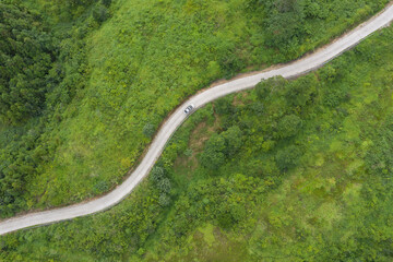 A white car was driving on the winding road at the top of the mountain