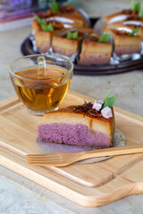 slice of homemade chiffon cake mix with Asian style dessert taro custard, can see layer and topping by fried onion served with tea on wooden board